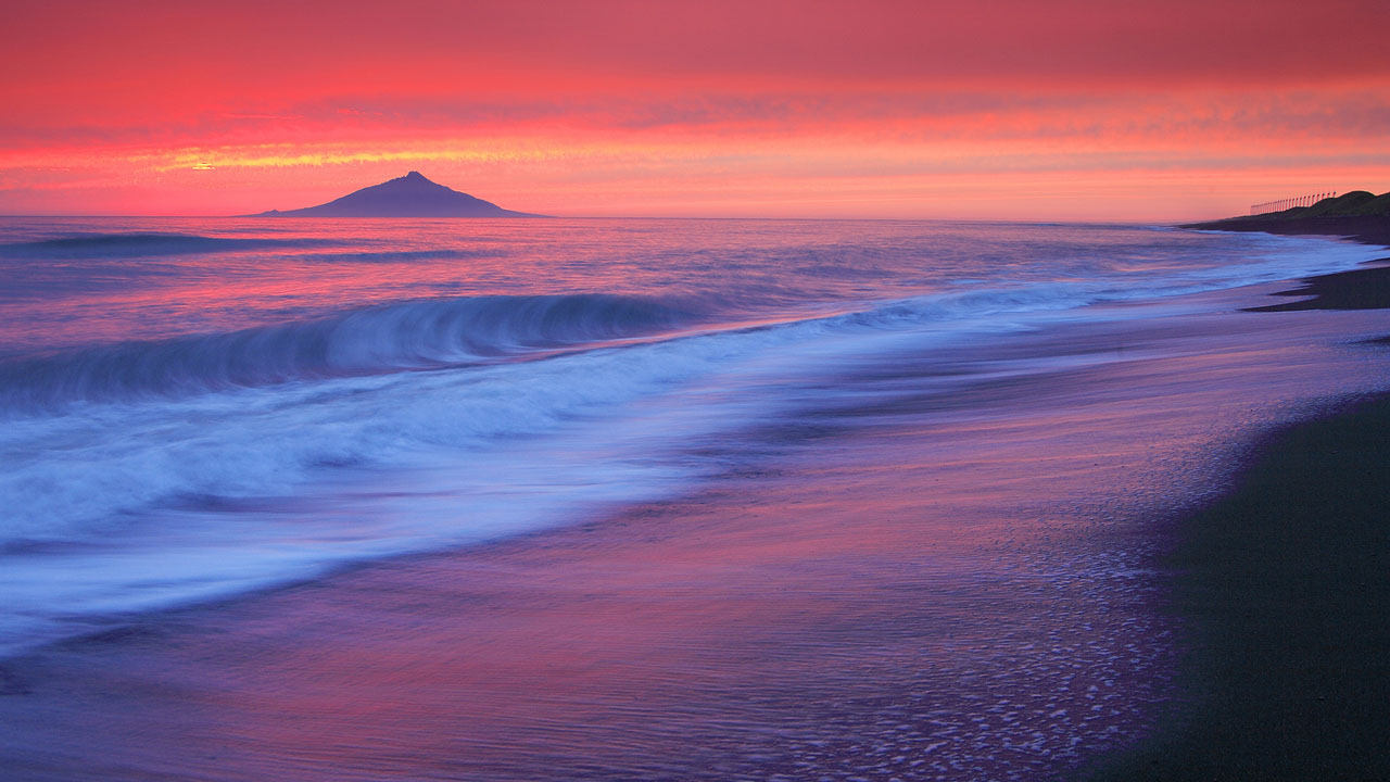 sun rising behind the blue sea wallpaper
